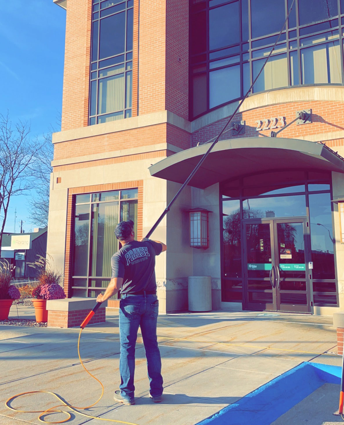 Praise Window Cleaner cleaning a commercial buildings windows with a long pole